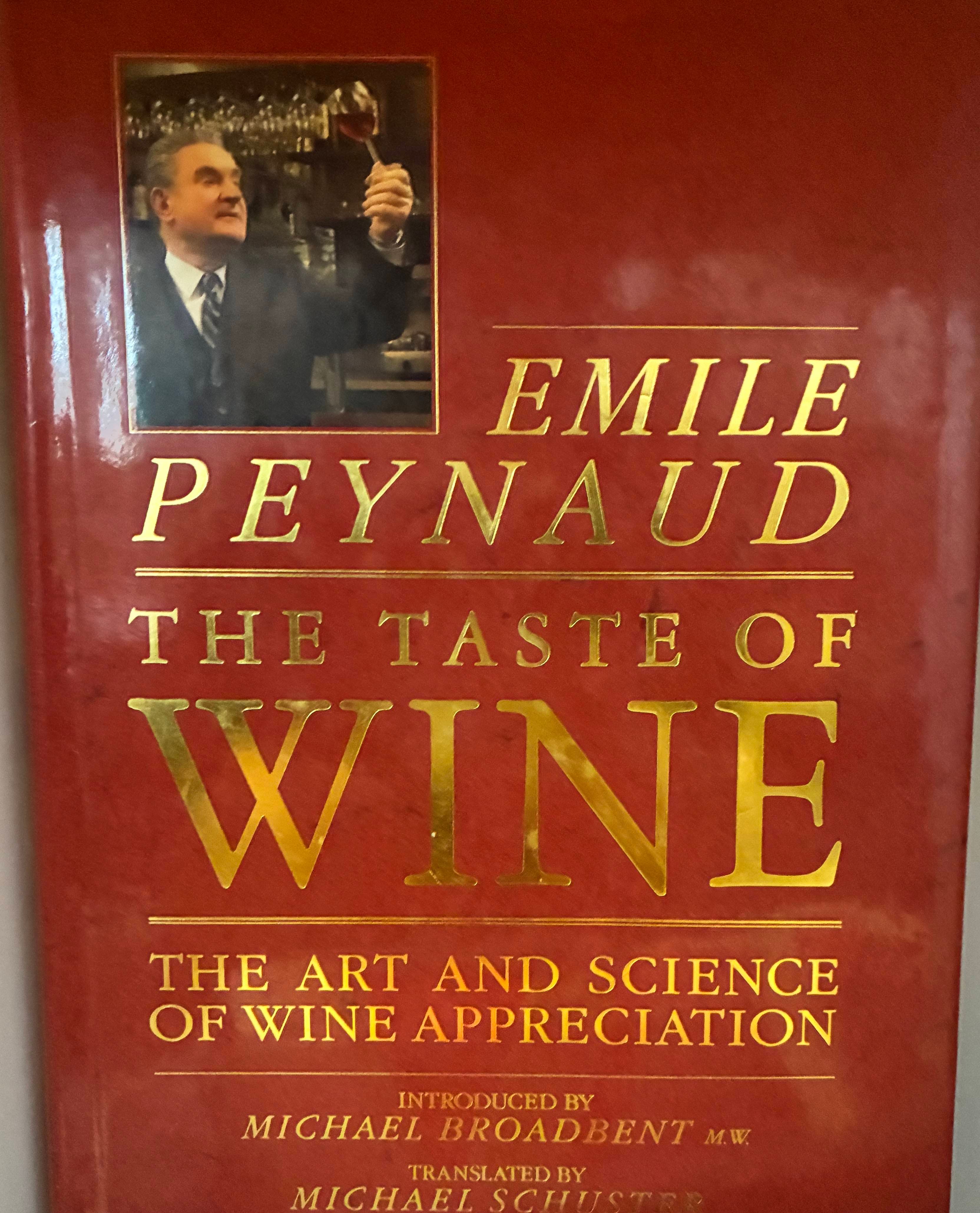 A close-up of the book "The Taste of Wine" by Emile Peynaud, featuring a photo of the author and a red cover with gold lettering.