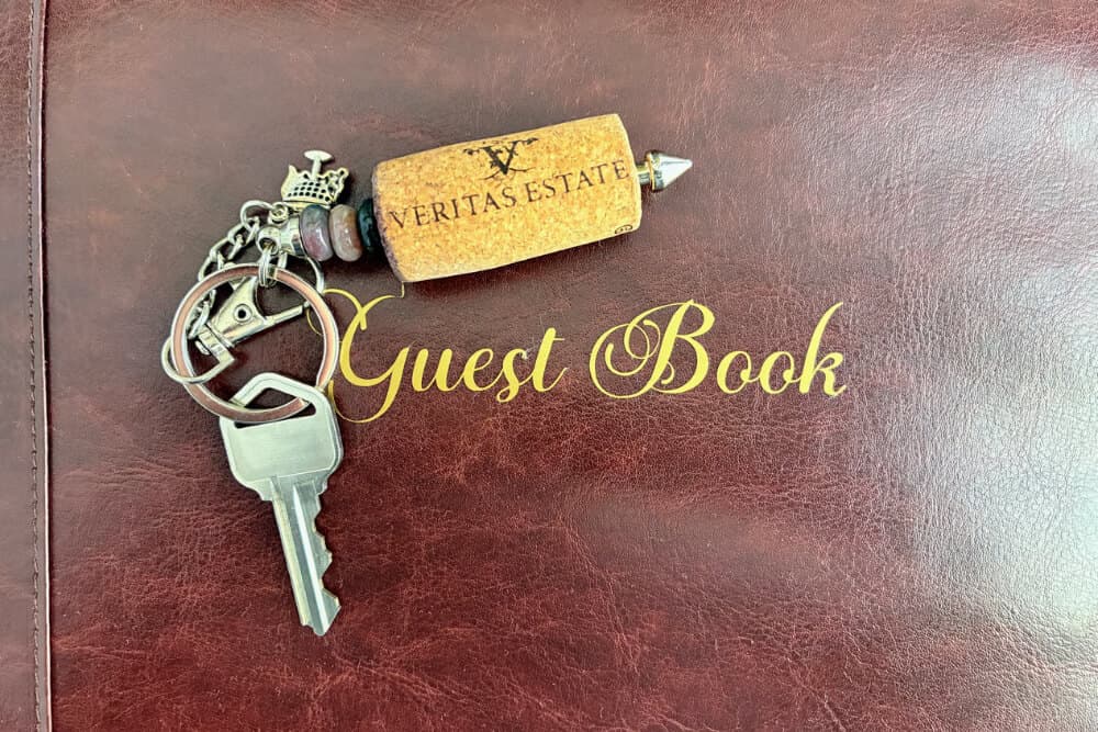 A cork with a logo and keychain resting on a leather guest book.