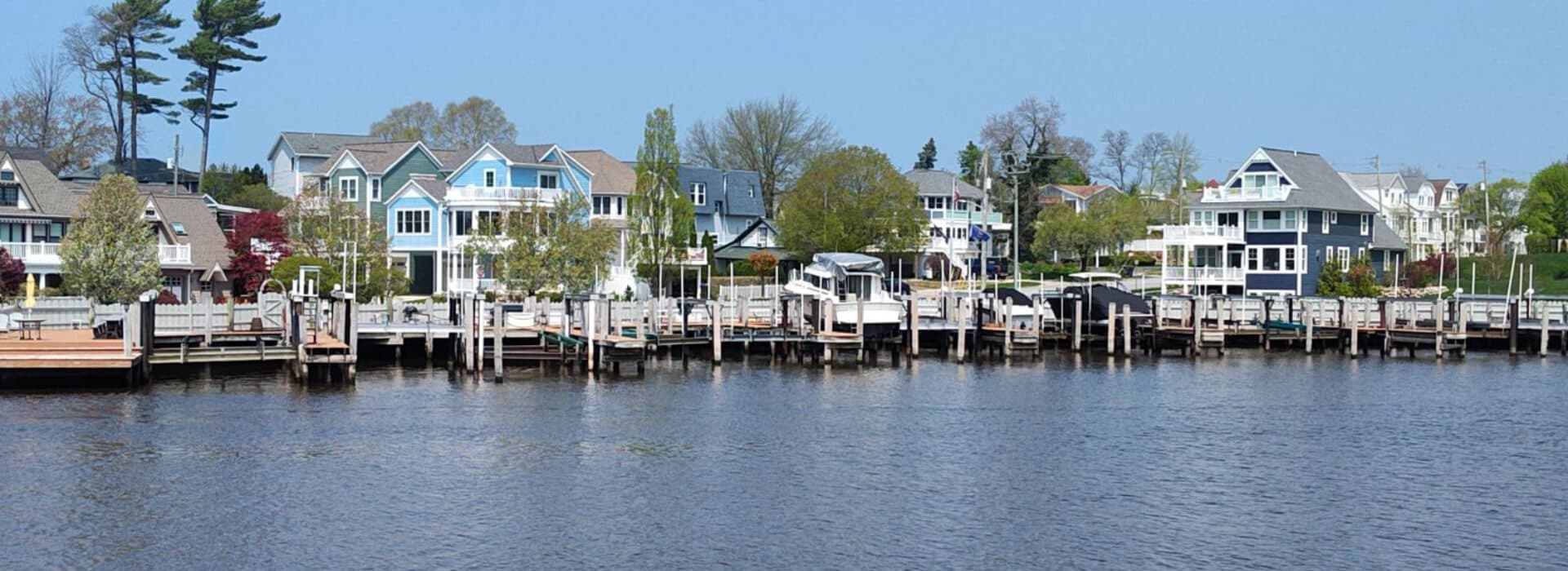Scenic waterfront homes line a dock along a calm river under a clear blue sky.