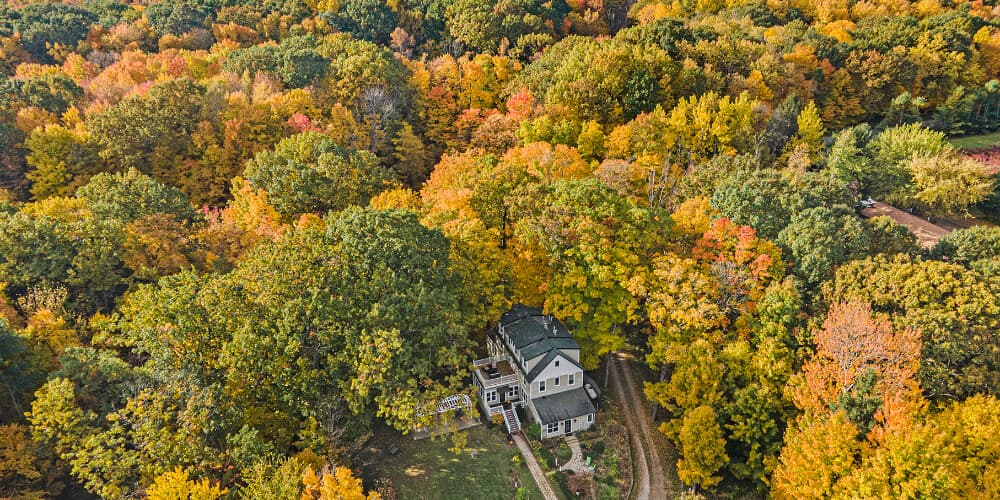 Aerial view of a house surrounded by vibrant autumn foliage.